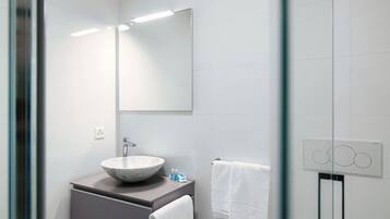 Un baño moderno con un espejo grande, un lavabo redondo de mármol y un perchero para toallas.