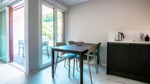 A modern kitchen with a dining area, featuring a table, chairs, and a kettle on the counter. - Studio with balcony near the center of Locarno (YELLOW STUDIO 12) (Locarno)