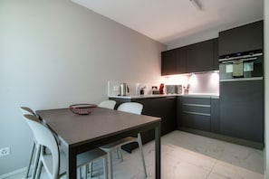 Une cuisine moderne avec un coin repas, comprenant une table, des chaises et une bouilloire.