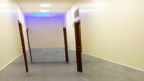 Un pasillo con piso gris y paredes blancas, que conduce a una puerta al final.