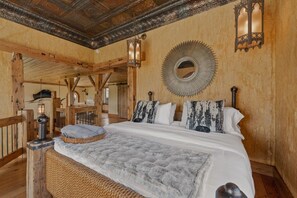 Ein rustikales Schlafzimmer mit einem großen Bett, Holzbalken, einem Spiegel und einer Laterne.