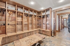 Un vestiaire avec des casiers en bois, des crochets en métal et un banc.