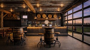 A rustic bar area with wooden barrels, a bar counter, and large windows offering a view. - Stay in a Real Castle on a Vineyard (Cleveland)