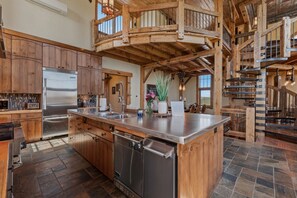 A spacious kitchen with a central island, wooden cabinetry, and a stainless steel refrigerator.