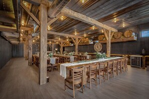 Un intérieur rustique avec des poutres en bois, une longue table à manger et des tabourets de bar.