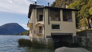 A two-story building with balconies overlooking a lake, a mountain in the background, and a clear sky. - Directly on Lago di Lugano with boat mooring (Porlezza)
