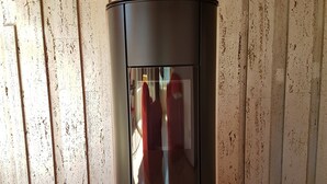 A modern, black wood-burning stove with a glass door, set against a textured wall. - Directly on Lago di Lugano with boat mooring (Porlezza)