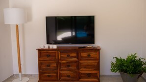 A wooden cabinet with drawers, a flat-screen TV on top, a floor lamp, and a potted plant.