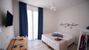 A bedroom with a bed, a wooden table, a TV, and a window with curtains. - Double Room 1 - Disabled (Pizzolungo)