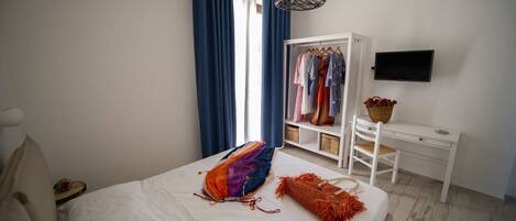 A bedroom with a bed, a wardrobe, a desk, and a television.