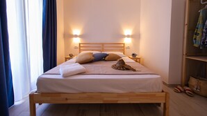 A neatly made bed with a wooden frame, two bedside tables with lamps, a wardrobe, and a window with curtains. - LANDLORD TIPINO (Pizzolungo)