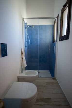 A bathroom with a toilet, bidet, and a glass-enclosed shower area. - LANDLORD TIPINO (Pizzolungo)