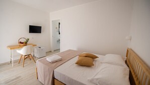 Ett sovrum med en säng, ett skrivbord, en stol, en tv och en korg med frukt.