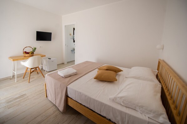 A bedroom with a bed, a desk, a chair, a TV, and a basket of fruit. - TIPINO'S OWNER'S TIP (Pizzolungo)
