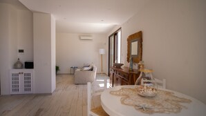 Une pièce spacieuse comprenant une table à manger, des chaises blanches, un canapé et un meuble en bois.