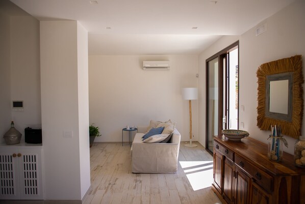 Una sala de estar moderna con un sofá, una mesita auxiliar, una lámpara y un mueble de madera.