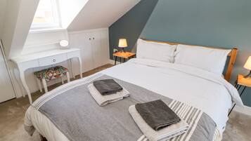 A bedroom with a bed, a desk, a chair, and a window.