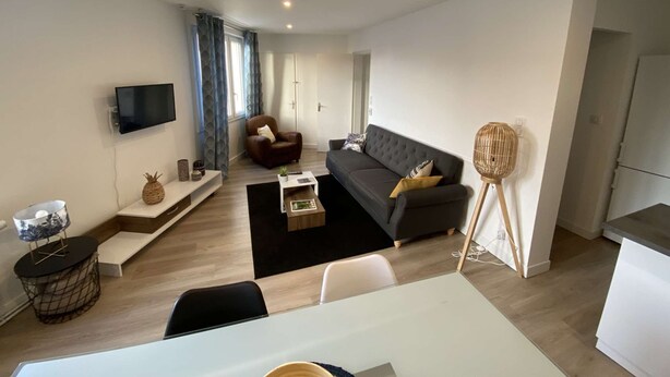Un salon moderne avec un canapé, une table basse et un téléviseur fixé au mur.