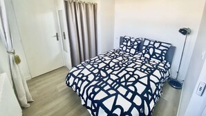 Une chambre à coucher avec un lit, des rideaux, une lampe sur pied et une porte.