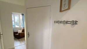 Un couloir avec un plancher en bois, une porte blanche et une citation inspirante encadrée au mur.