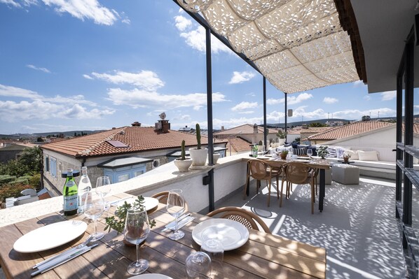 A rooftop terrace with a dining table set for two, a potted plant, and a bottle of wine. - Alle Alacati (Cesme)