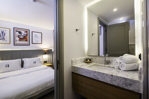 A hotel room with a bed, a marble bathroom vanity, a sink, and a large mirror. - Alle Alacati (Cesme)