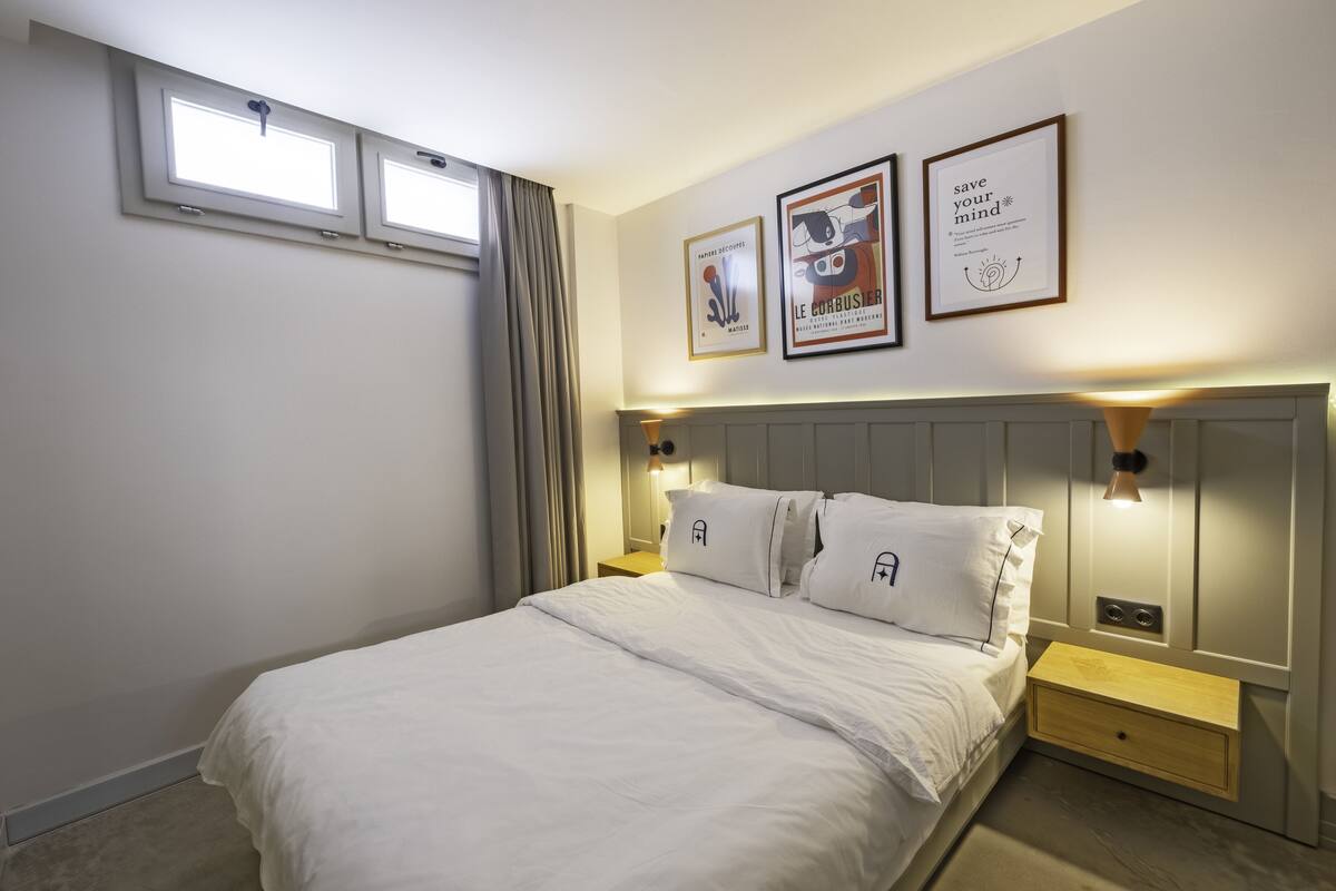 A neatly arranged bedroom with a bed, bedside tables, and wall-mounted lights.