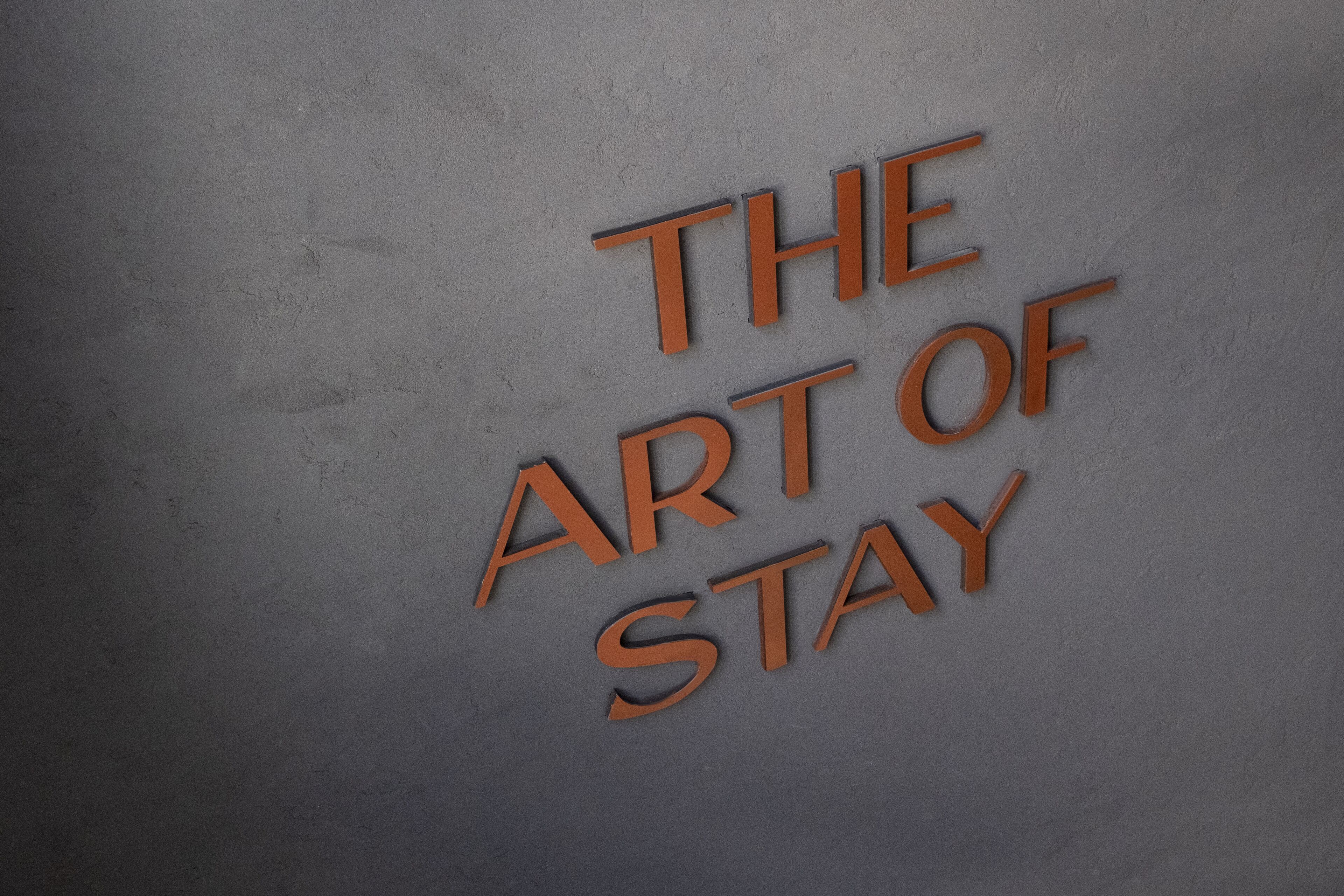 Een muur met de tekst 'THE ART OF STAY' in oranje letters.
