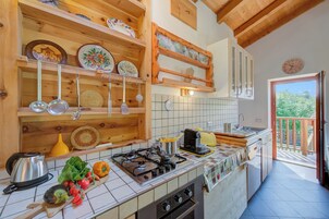 Una cocina con estantes de madera, una estufa a gas y vistas al exterior.
