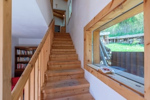 A wooden staircase leading to a room with a window overlooking a garden. - Casa Tra Borgo e Lago in Lake Tenno (Tenno)
