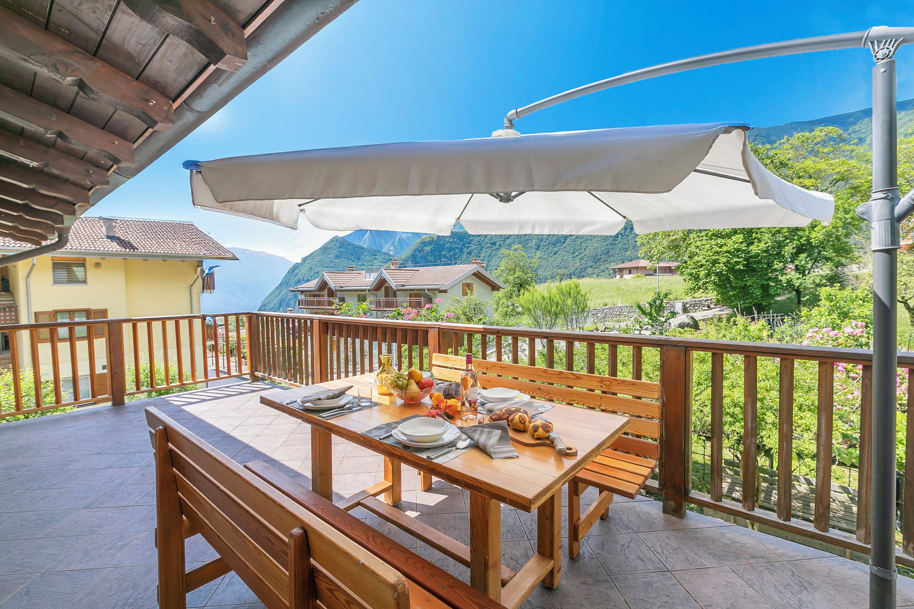 A wooden table set outdoors with a view of mountains and houses in the background.