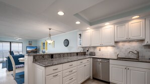 A modern kitchen with white cabinets, granite countertops, and a dishwasher. - Beautiful Two Bedroom Oceanfront Great Mid Town Location! (Ocean City)