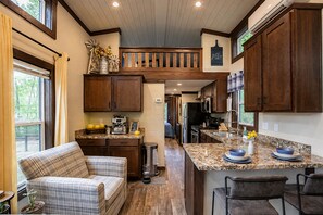 A modern kitchen with wooden cabinets, granite countertops, and a central island with bar stools.