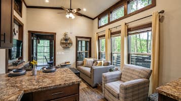 A spacious living area with a large window, a ceiling fan, and a cozy seating arrangement.
