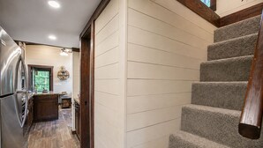A kitchen with a stainless steel refrigerator, wooden cabinets, and a window with a view. - Wildwood Den at The Retreat at Water's Edge (Tracy City)