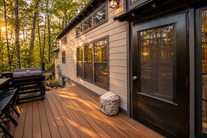A deck with a grill, outdoor seating, and a covered area with a door.