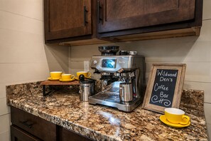 Un café doté d’une machine à expresso de marque Besville, de tasses jaunes et d’un panneau d’affichage en ardoise.
