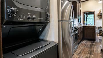 Eine Küche mit einem Edelstahl-Kühlschrank, einem Backofen und einer schwarzen Dunstabzugshaube.