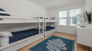 A room with bunk beds, a desk, a TV, and a window with blinds. - White Sands Retreat - Pool/Hot Tub/Walk to Beach! (St. Augustine Beach)