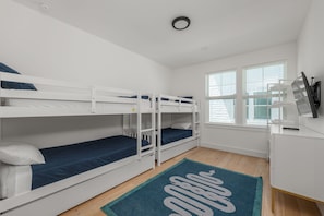 A room with bunk beds, a desk, a TV, and a window with blinds. - White Sands Retreat - Pool/Hot Tub/Walk to Beach! (St. Augustine Beach)