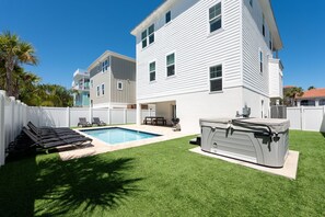 Un jardin avec une piscine, un jacuzzi et un espace patio couvert.