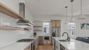 A modern kitchen with white cabinetry, stainless steel appliances, and wooden flooring. - White Sands Retreat - Pool/Hot Tub/Walk to Beach! (St. Augustine Beach)