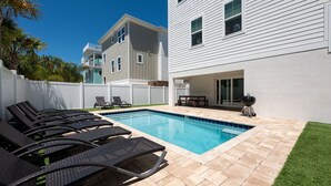 A swimming pool with lounge chairs, a barbecue grill, and a covered patio area. - White Sands Retreat - Pool/Hot Tub/Walk to Beach! (St. Augustine Beach)