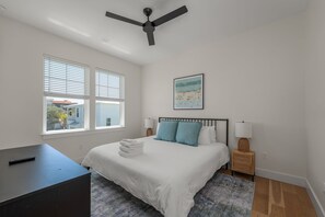 Une chambre à coucher avec un lit, des lampes de chevet, un bureau et un ventilateur de plafond.