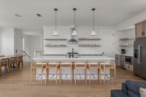 Une cuisine moderne avec un îlot central, des luminaires suspendus et des chaises en bois.
