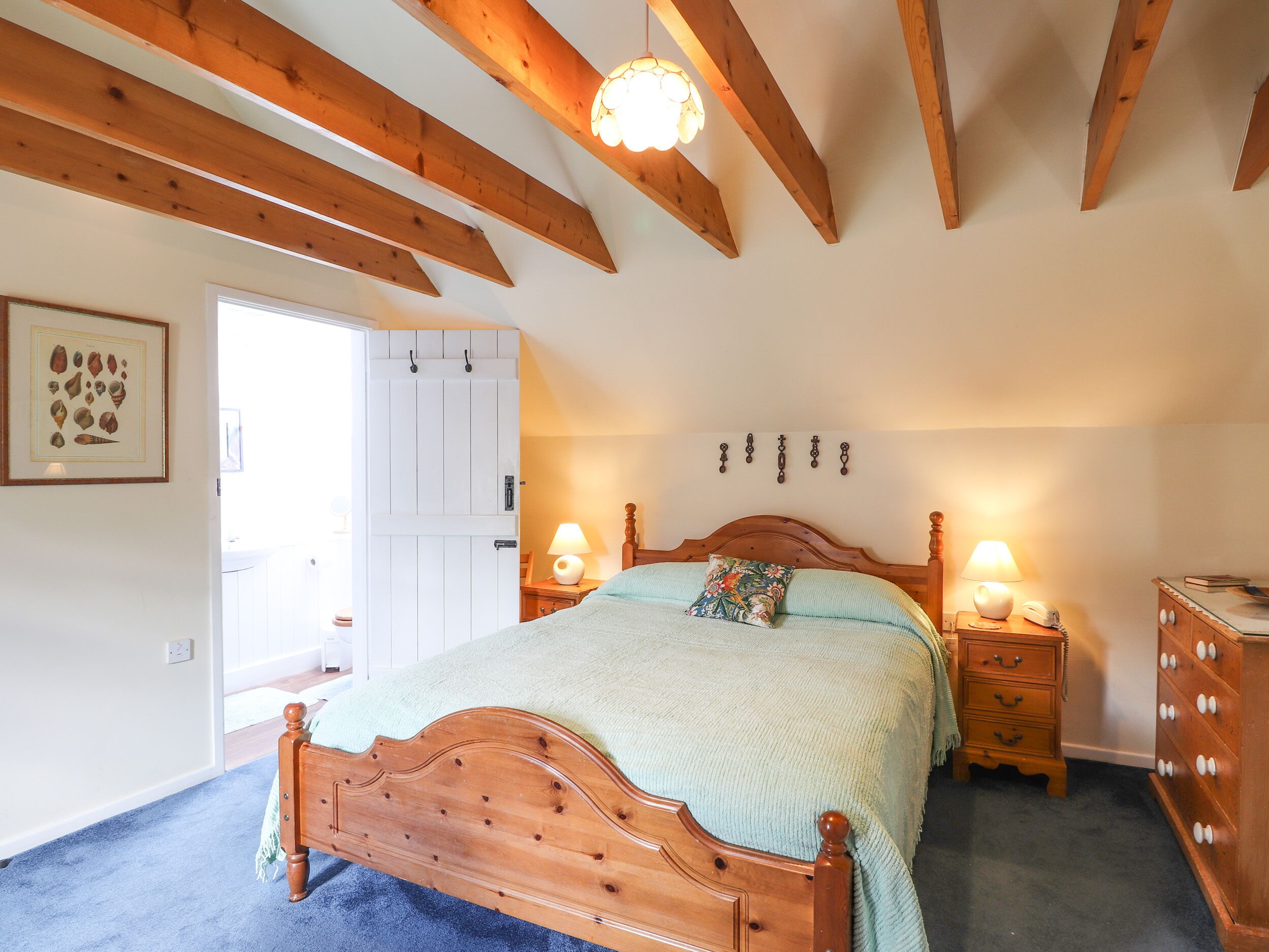 Une chambre à coucher avec un lit en bois, deux tables de chevet avec des lampes, une commode et une porte avec un panneau blanc.