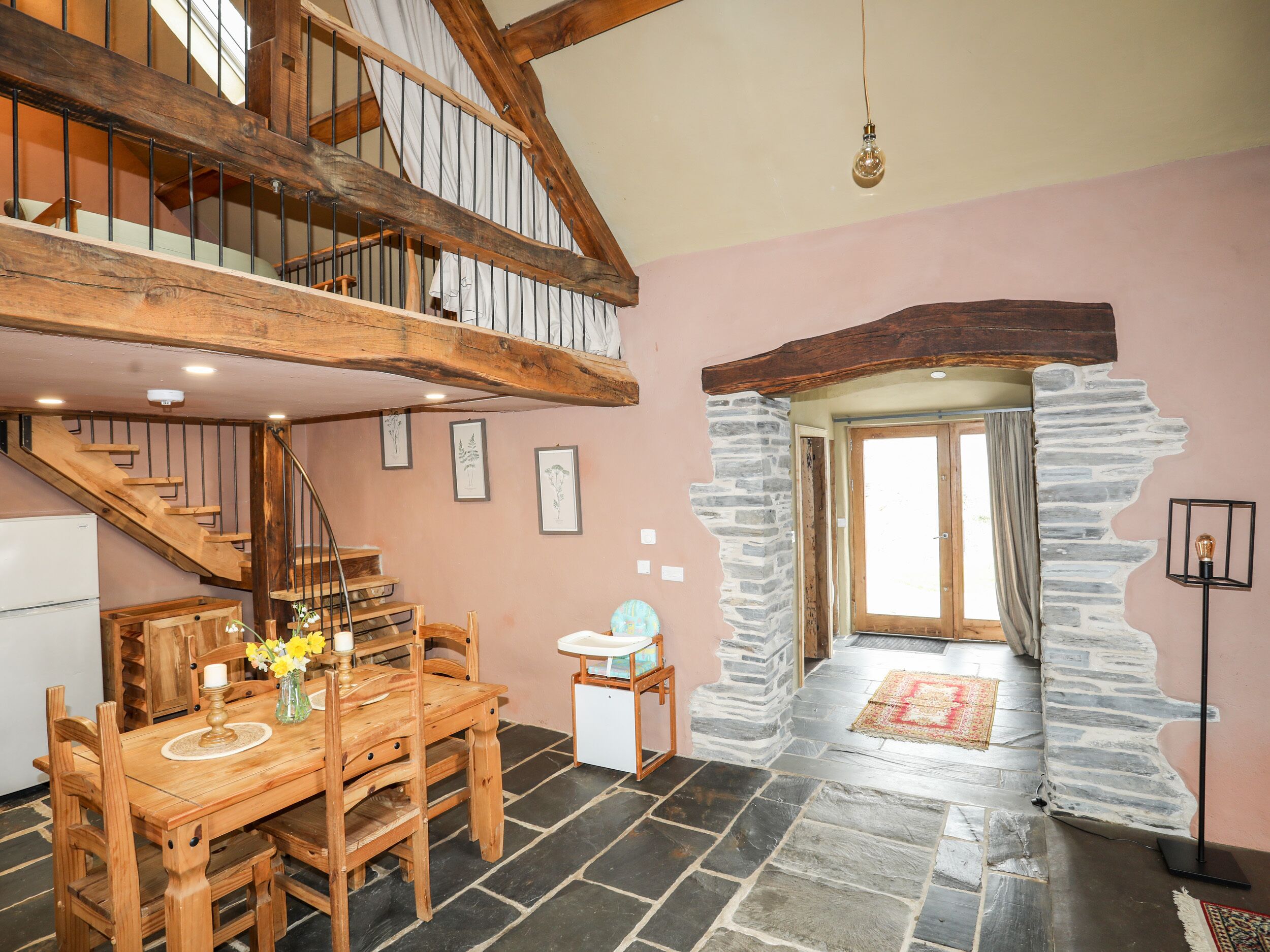 Una escalera de madera con un arco de pared de piedra que conduce a una habitación con piso de piedra.