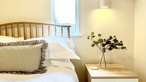 Una camera da letto con un letto, un comodino, una lampada e una finestra.
