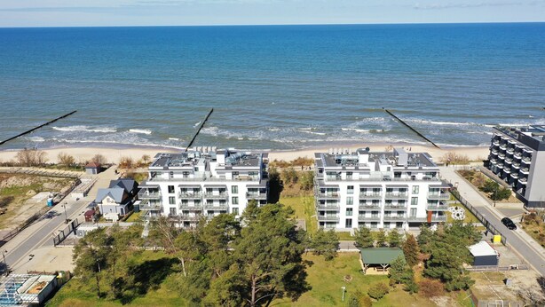 A coastal hotel with multiple floors, a beach view, and a parking area. - Apartamenty Sun & Snow Jantaris (Mielno)