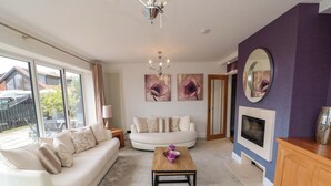 A living room with a sofa, a coffee table, a fireplace, and a large window. - Wyvill House (Scarborough)